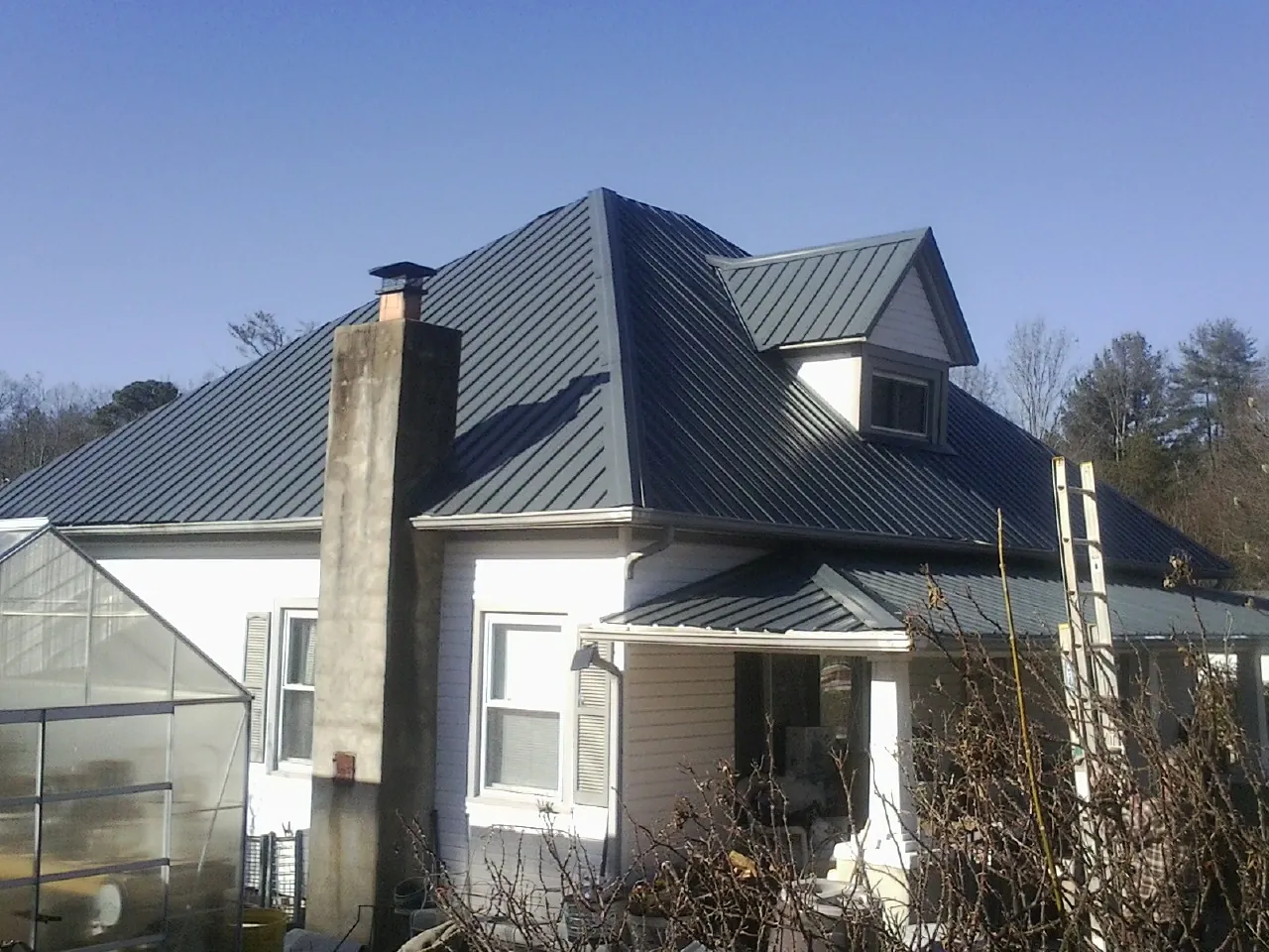 Dark blue standing seam metal roof on a white farmhouse with dormer — Slate & Tile Roof Repair by Roofing Brothers in Scotland Neck