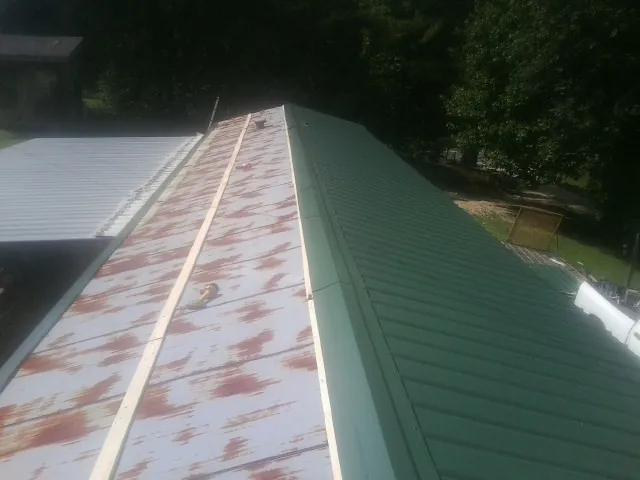Old rusted panels beside newly installed green metal roofing — Wind Damage Roof Repair by Roofing Brothers in Scotland Neck