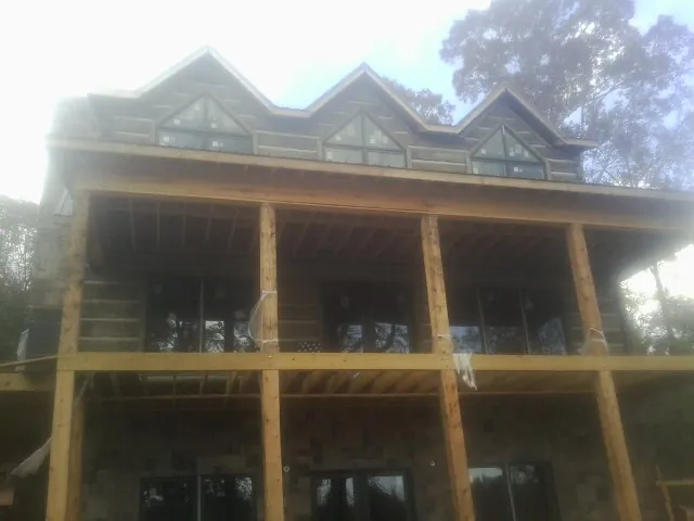 Dormers and porch framing on a large log home under construction — Roof Coating work by our crew in Scotland Neck