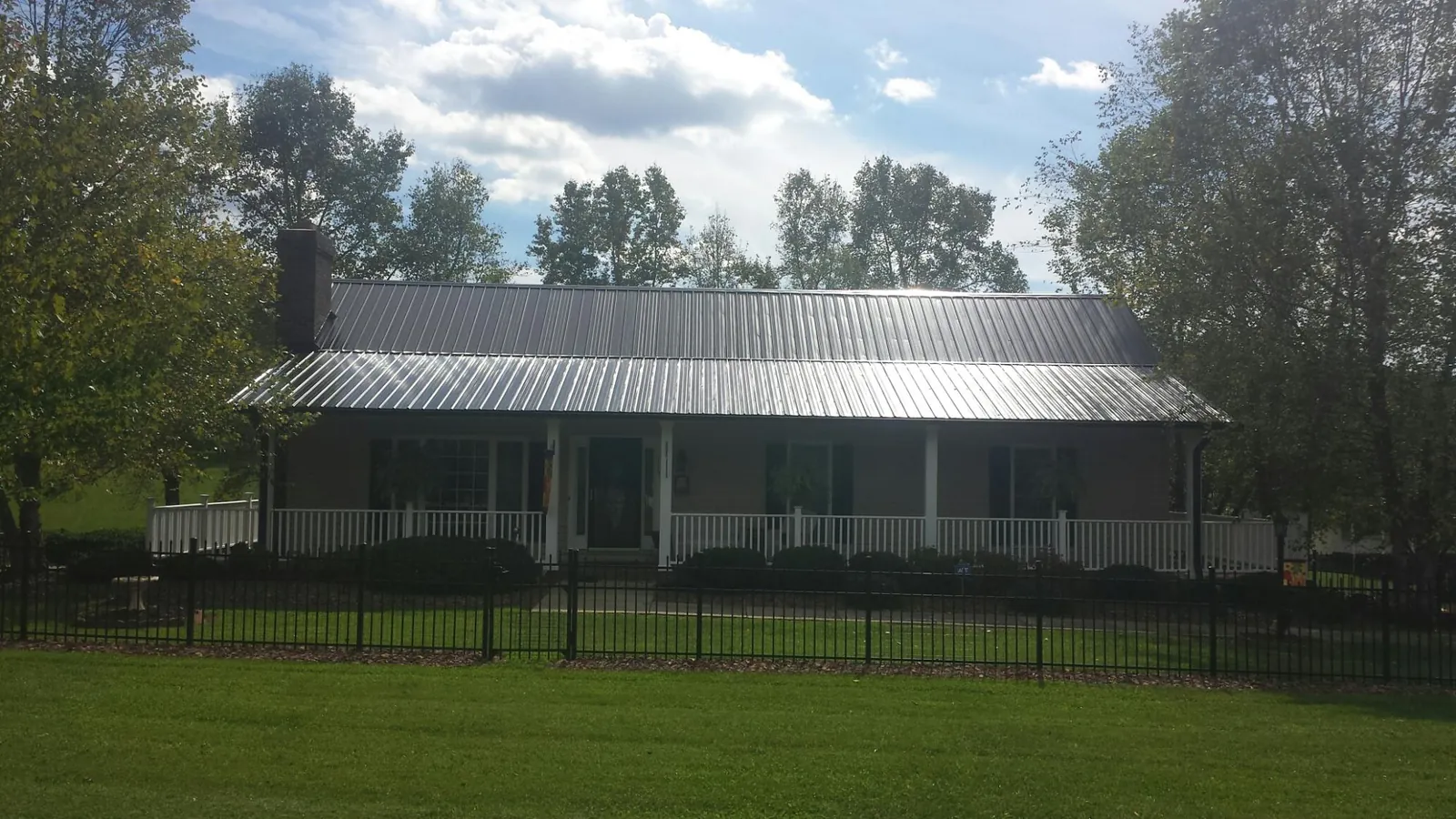 Gray metal roof on a brick ranch with a full width front porch — Gutter Guard Installation work by our crew in Scotland Neck