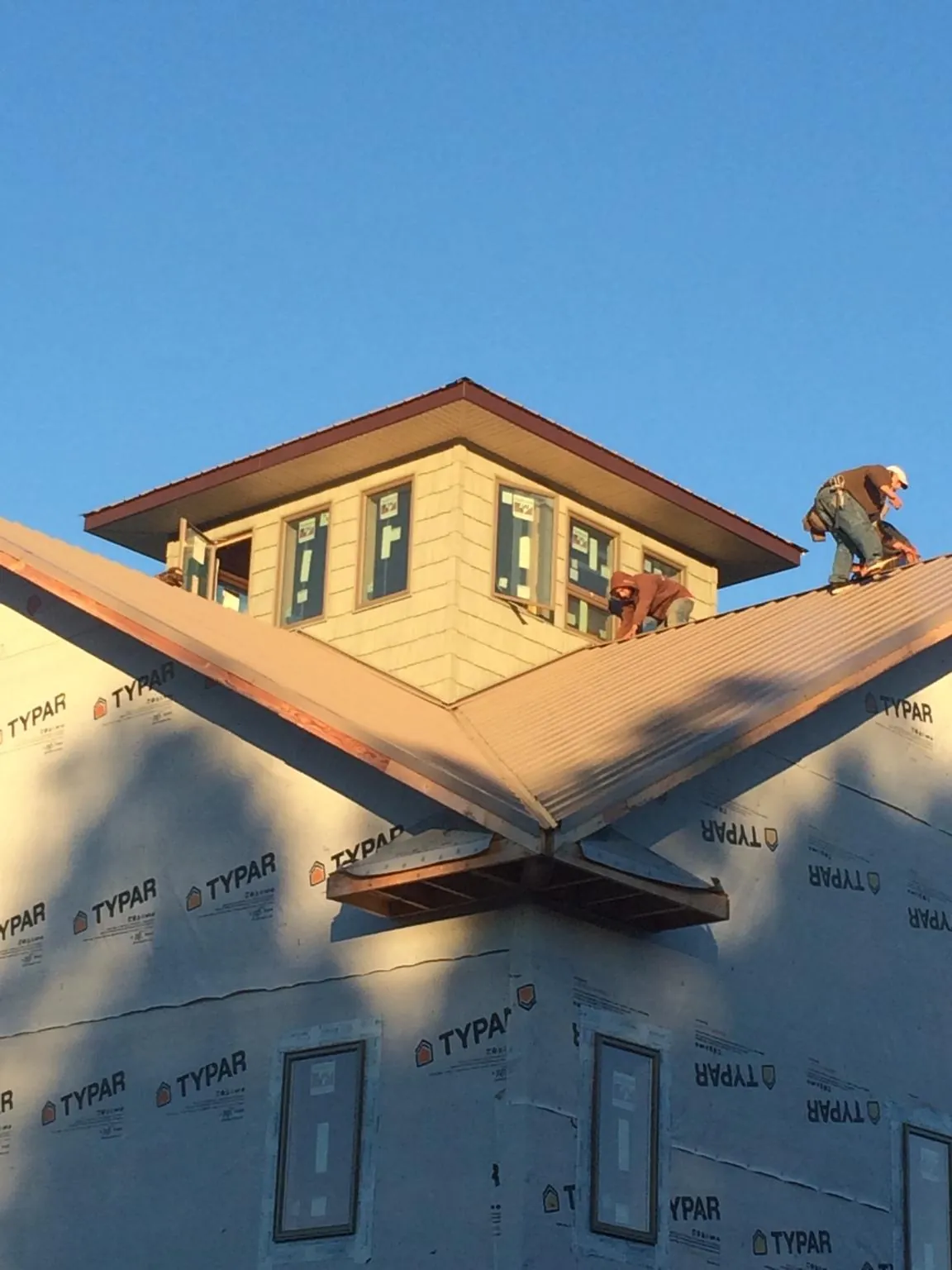 Roofers working around a rooftop cupola on a new metal roof at sunset — Roof Waterproofing in Scotland Neck by Roofing Brothers